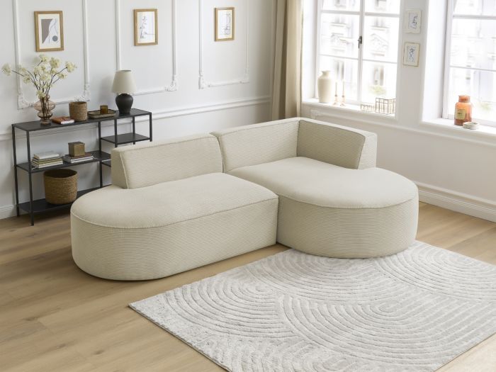 Canapé Rousseau beige vu de côté, formes arrondies, dans salon blanc clair.