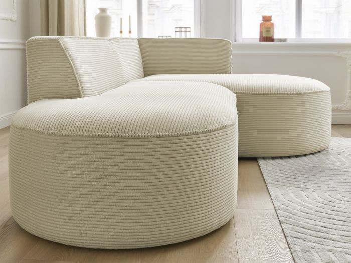 Gros plan des coussins et accoudoirs du canapé Rousseau beige en tissu côtelé.