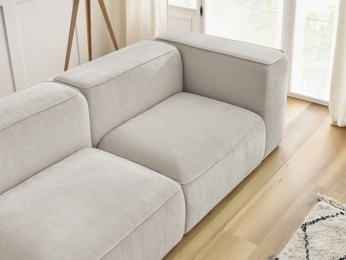 Gros plan sur les coussins et modules du canapé Zephyr en tissu beige clair.