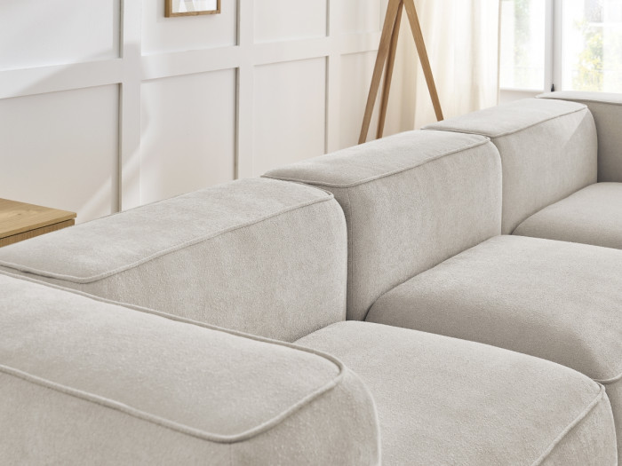Détail des accoudoirs et coussins du canapé Zephyr en tissu beige clair vue rapprochée.
