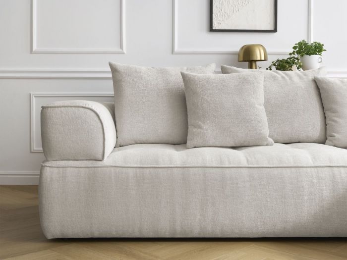 Canapé Whesley en tissu beige vue de côté, accoudoir et coussins décorés visibles