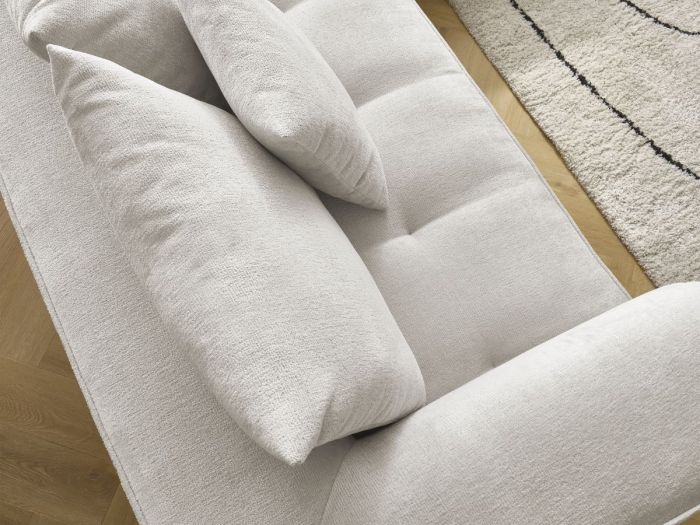 Gros plan sur la méridienne avec coussins en tissu beige texturé, détail de la matière