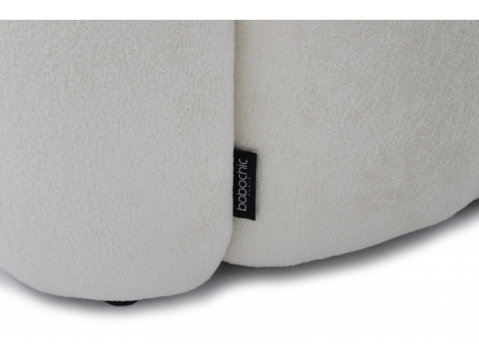 Gros plan du bouton de marque entre deux coussins du canapé Curvy blanc