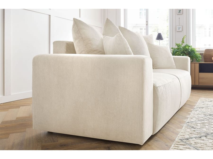 Canapé Envy beige vu de côté, montrant l'accoudoir arrondi et les coussins
