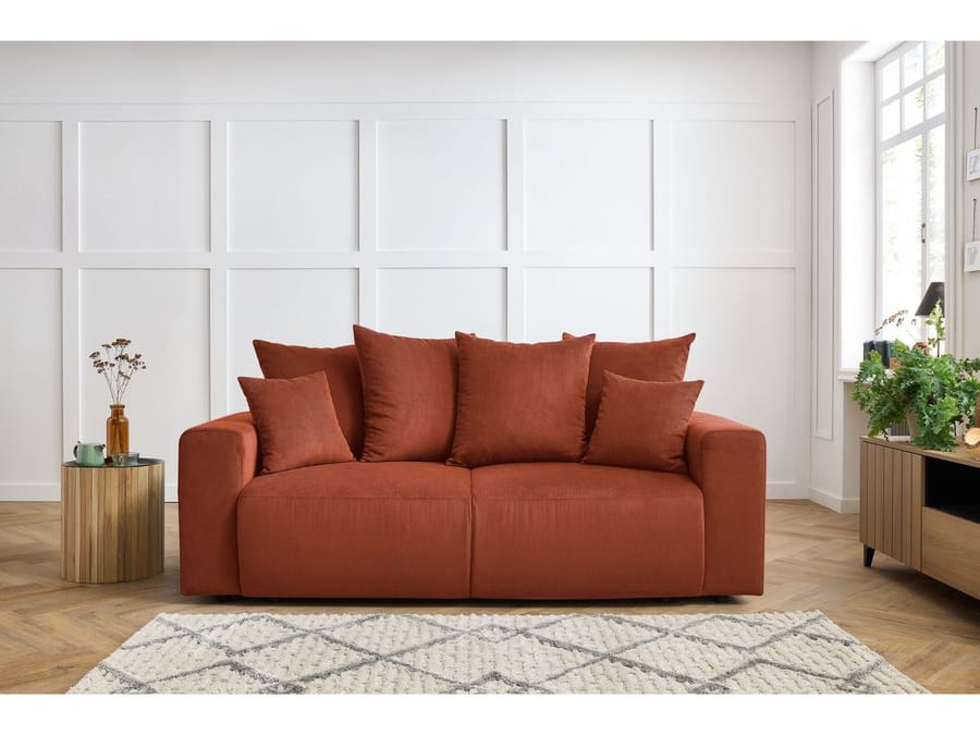 Canapé Envy terracotta dans un salon avec mur blanc panneauté et tapis gris