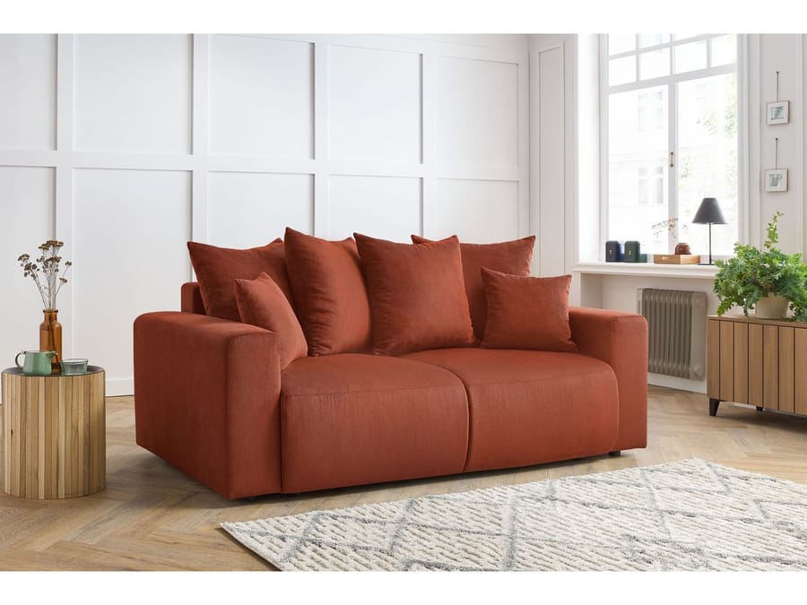 Canapé Envy terracotta dans un salon lumineux avec tapis et table basse bois