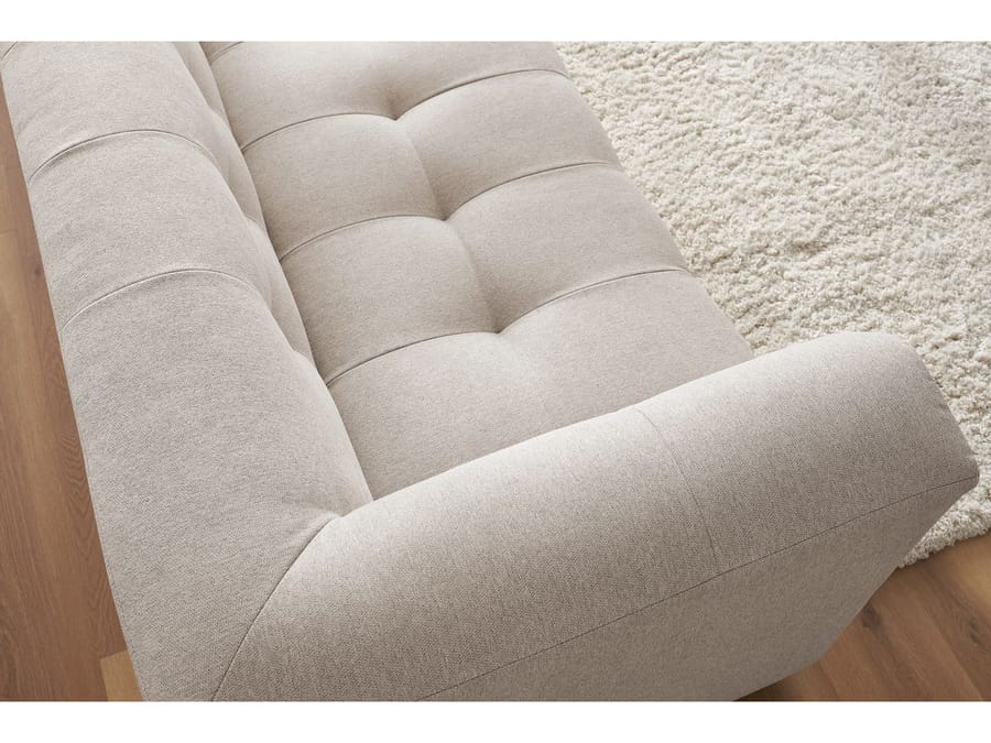 Gros plan sur les coussins matelassés du canapé Kleber en tissu beige et l accoudoir.