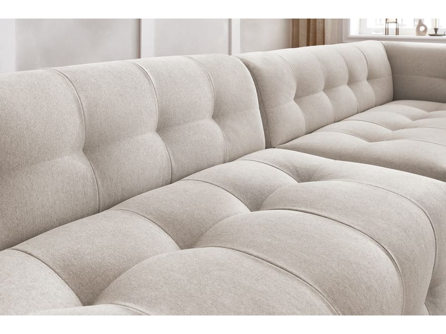 Gros plan sur la texture matelassée et les coutures du canapé Kleber en tissu beige.