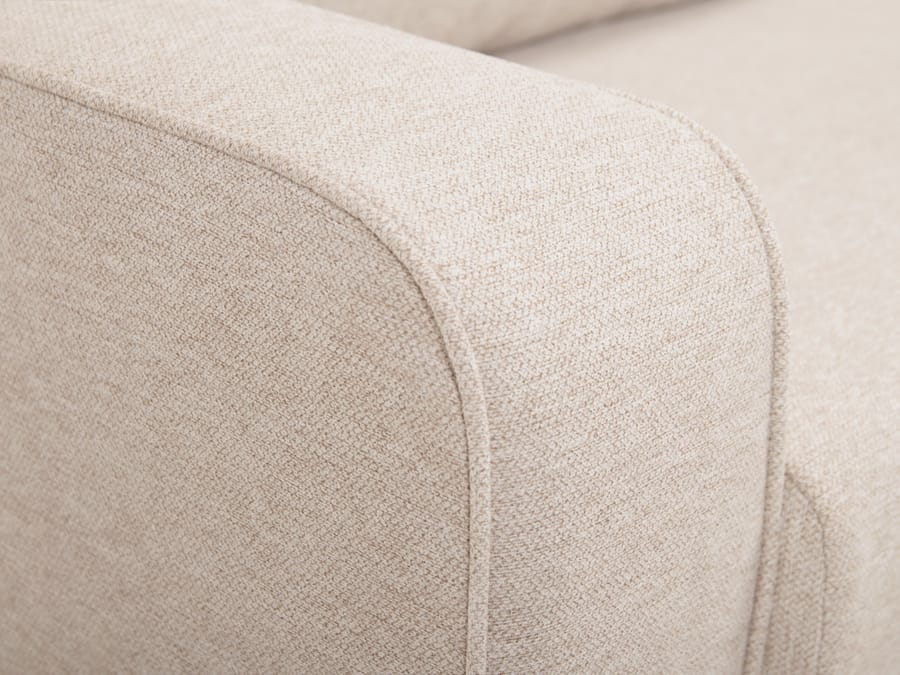 Gros plan sur l'accoudoir et le tissu beige du canapé Come avec coutures.