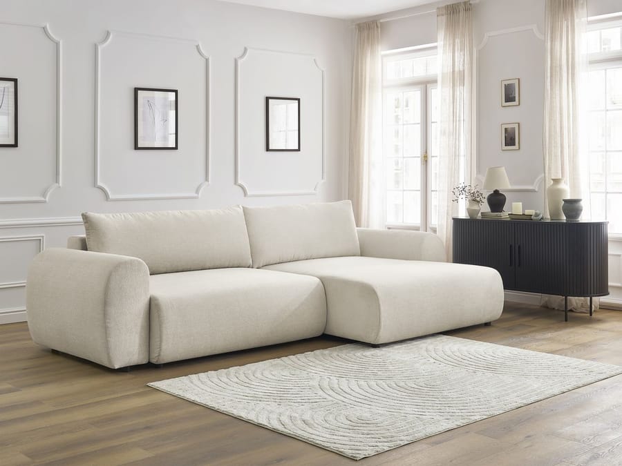 Canapé Lucien gris clair avec méridienne, positionné dans un salon lumineux avec mobilier noir