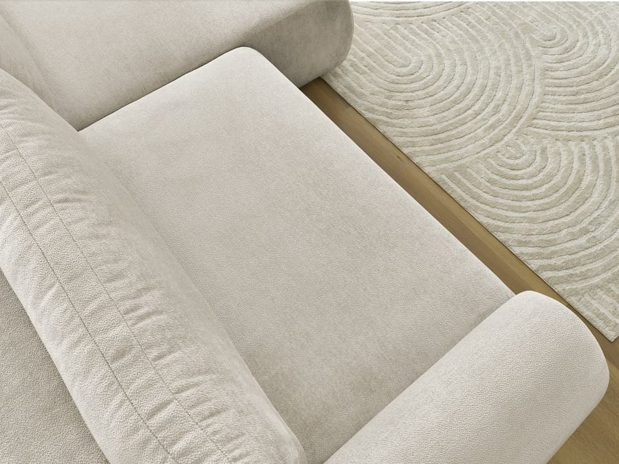 Gros plan sur les coussins et accoudoirs arrondis du canapé Lucien en tissu beige