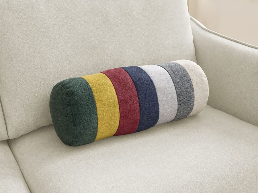 Coussin cylindrique coloré placé sur l'assise du canapé Lenny beige.