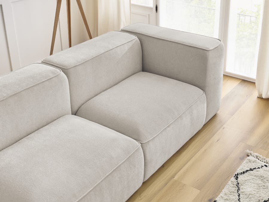 Gros plan sur les coussins et modules du canapé Zephyr en tissu beige clair.