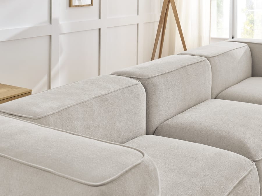 Détail des accoudoirs et coussins du canapé Zephyr en tissu beige clair vue rapprochée.