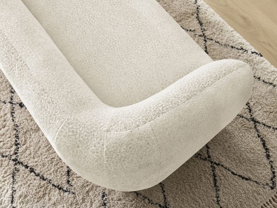 Gros plan sur l'accoudoir arrondi et le siège du canapé Celine beige.