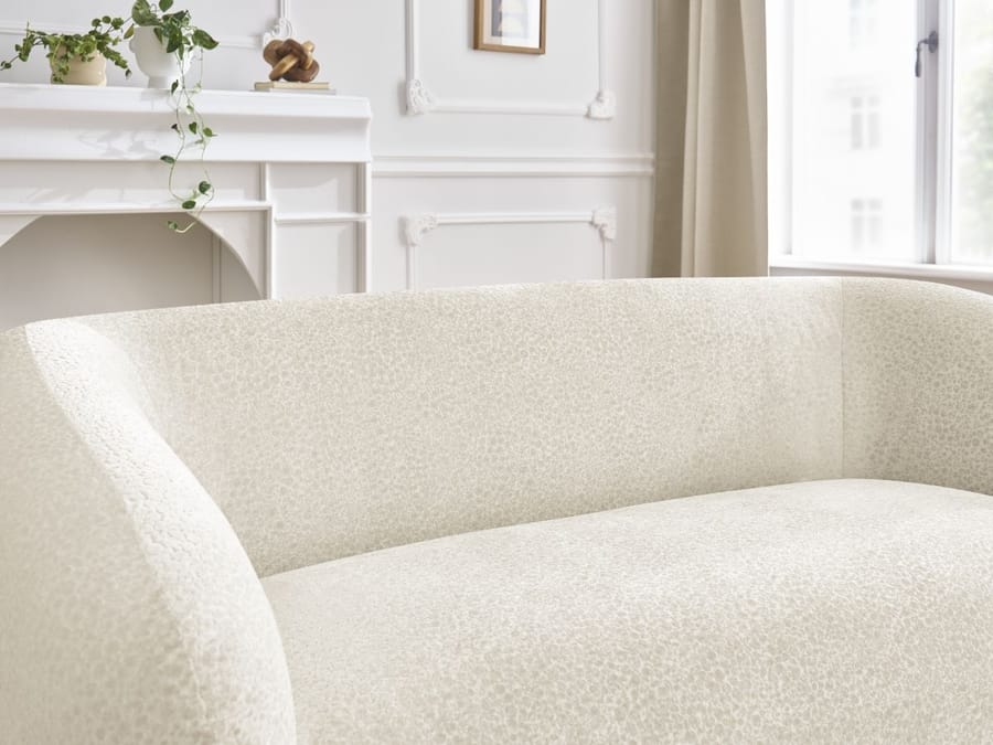 Détail des formes arrondies et de la structure du canapé Celine beige.