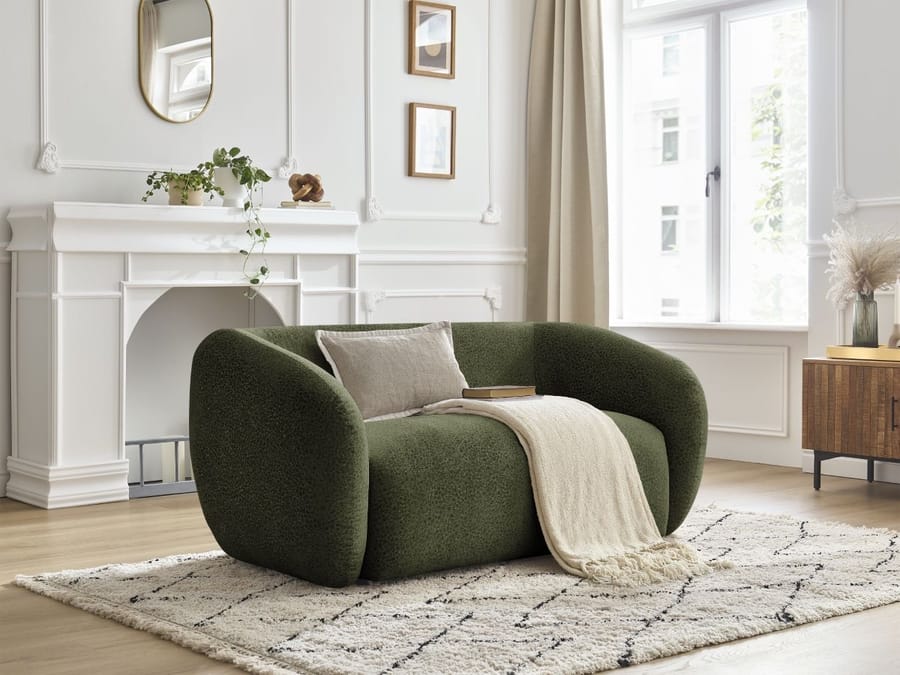 Canapé Celine vert foncé dans un salon blanc avec cheminée et décoration.