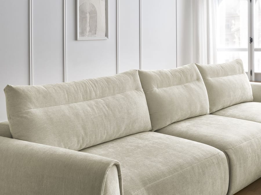 Gros plan des coussins et accoudoir du canapé Aden en tissu beige texturé