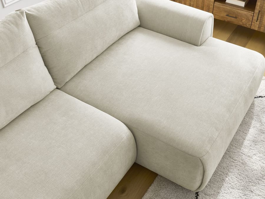 Gros plan de l'angle et des coussins du canapé Aden beige avec stitching visible
