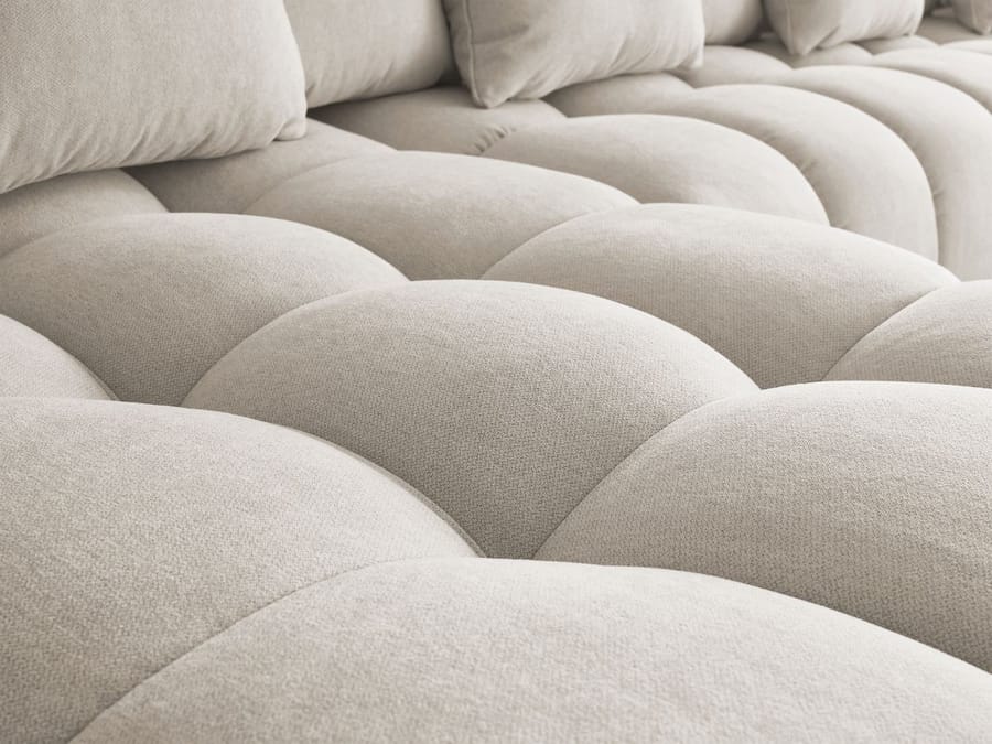 Gros plan des coussins gonflés du canapé Mont-Blanc en tissu beige clair.