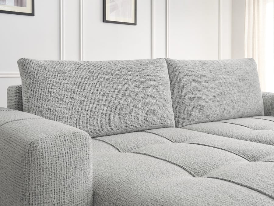 Gros plan des coussins et de la structure capitonnée du canapé Arsène gris clair.