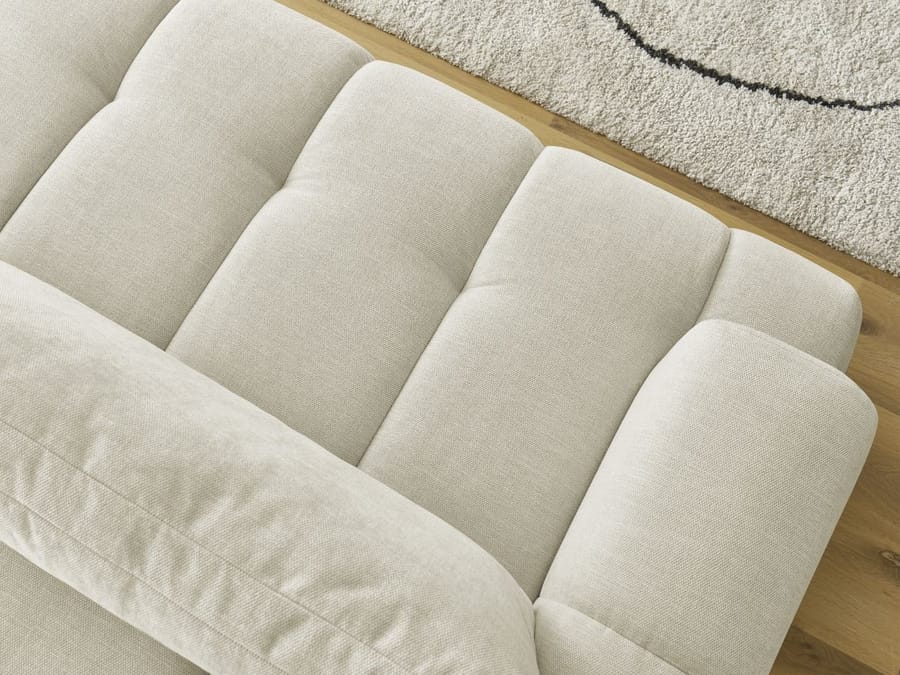 Gros plan des coussins bombés du canapé Fuji en tissu beige clair.