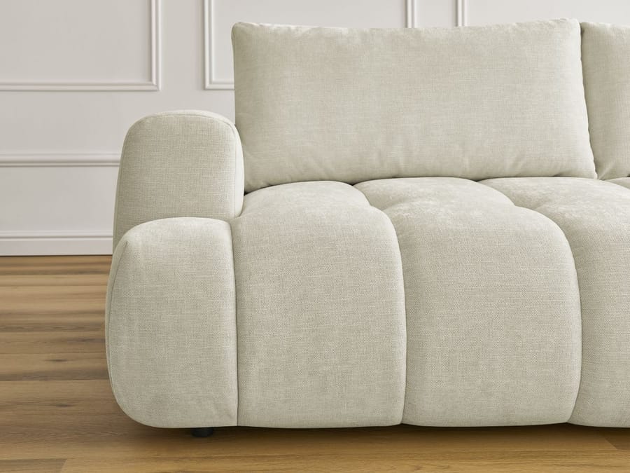 Gros plan de l'accoudoir arrondi et des coussins du canapé Fuji beige.