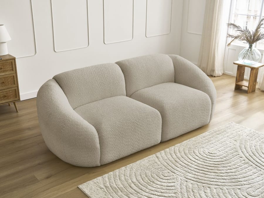 Canapé Tina en tissu beige clair vu de trois quarts, profondeur visible.