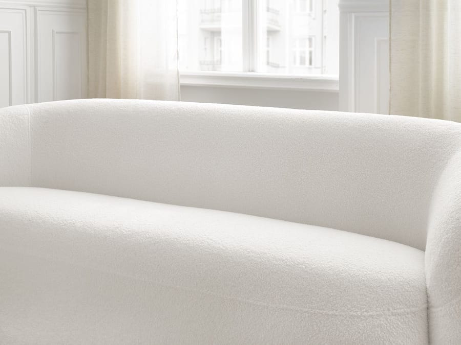 Gros plan sur l'accoudoir et le coussin du canapé Elina blanc.