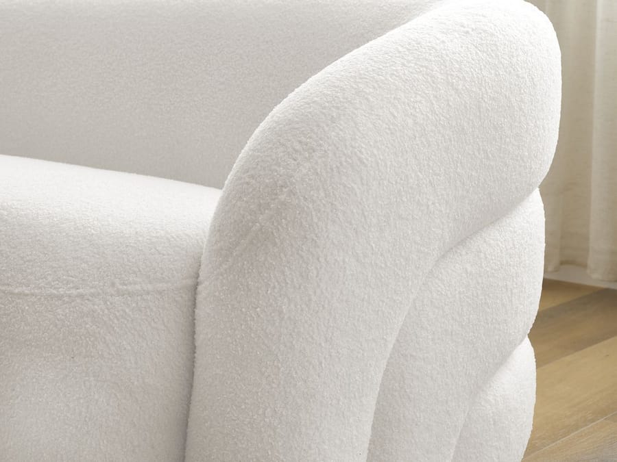 Gros plan sur l'accoudoir arrondi blanc du canapé Elina, texture textile visible.