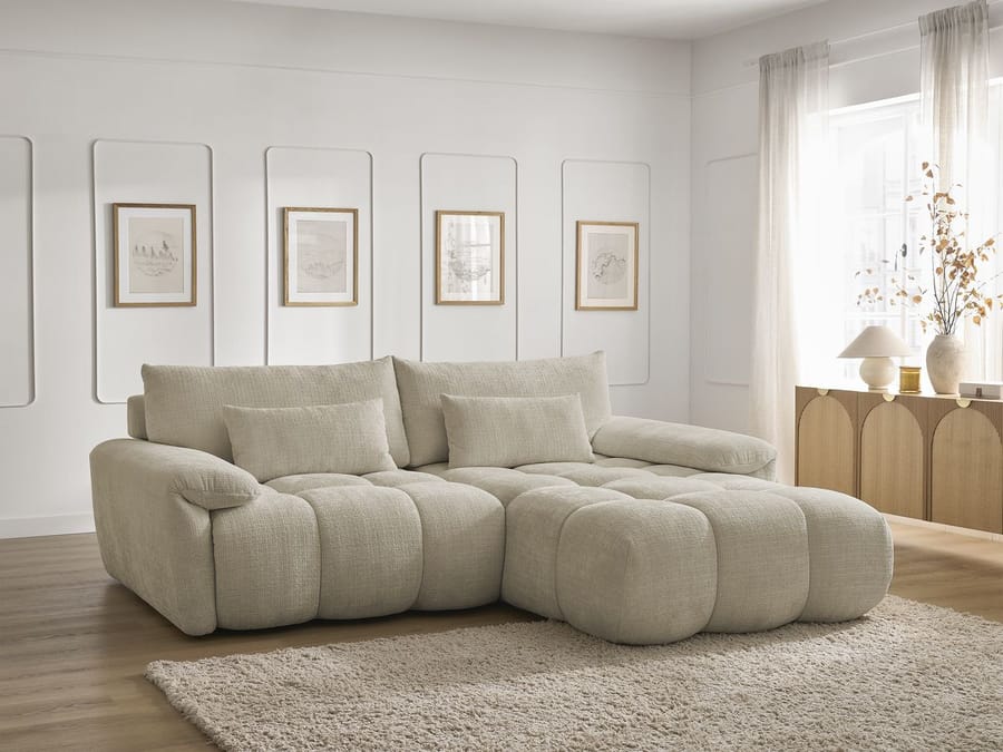 Canapé Ivane d'angle en tissu beige dans un salon clair avec tableaux encadrés.