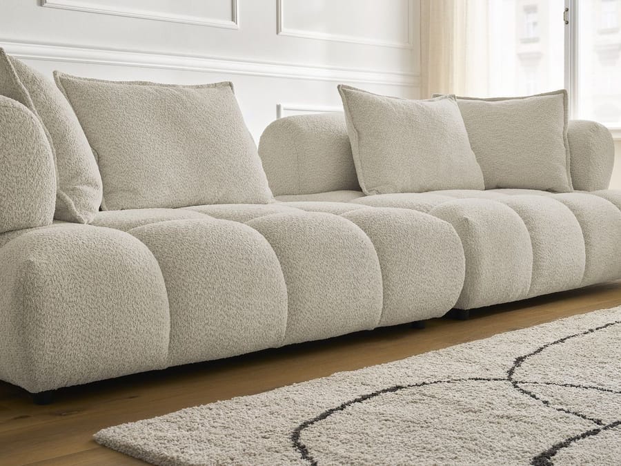 Détail des coussins bombés et des coutures du canapé Alya en tissu beige clair.