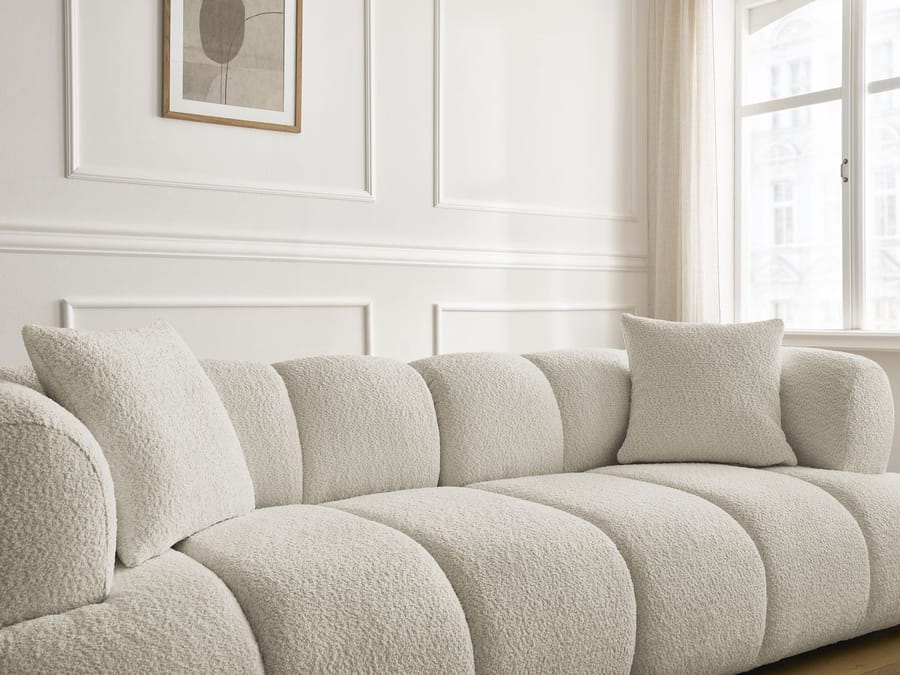 Détail du canapé Pamira beige montrant le capitonnage arrondi avec coussins de décoration