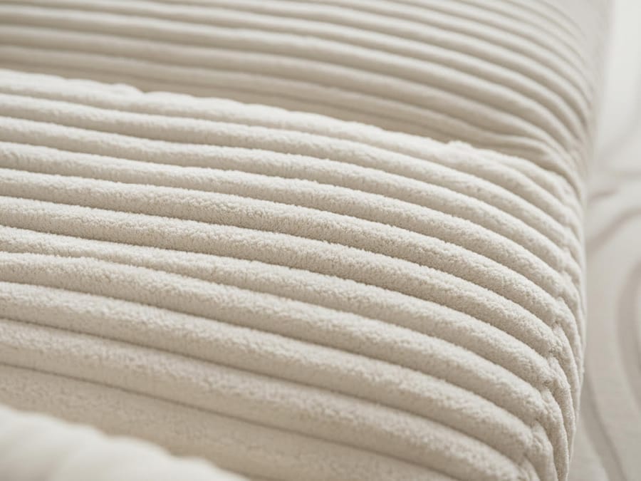 Gros plan du revêtement en tissu côtelé texturé du canapé Belem, coloris beige.