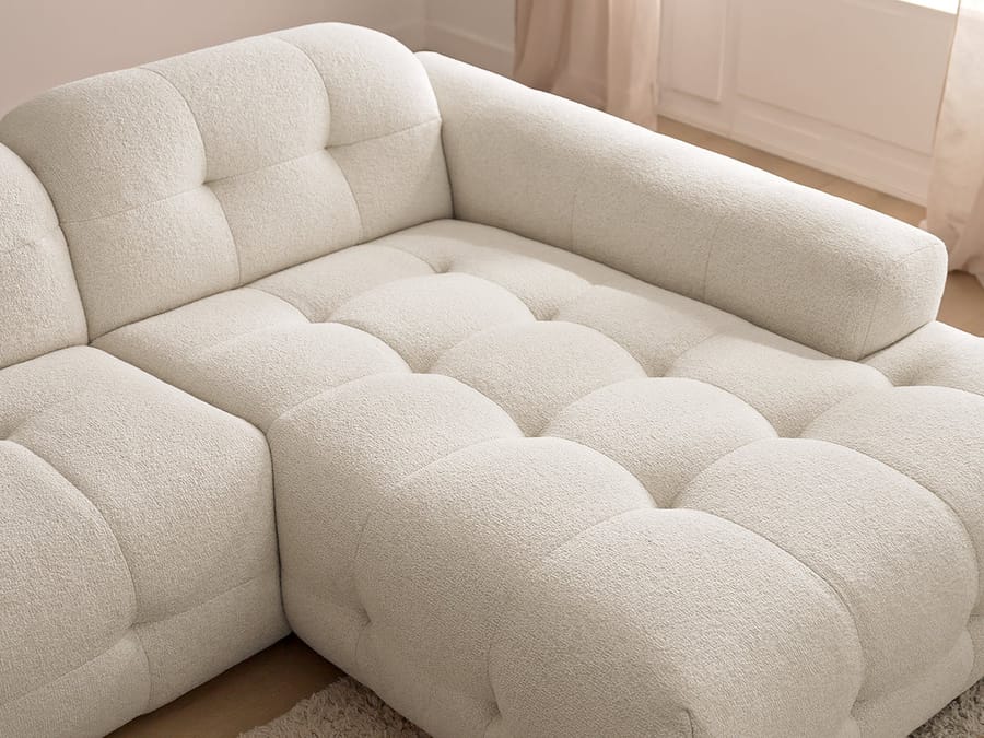 Gros plan sur les coussins capitonnés et la texture du tissu beige du canapé Laura.