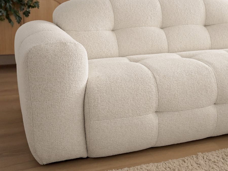 Détail du bras arrondi et des coussins gonflants du canapé Laura beige.