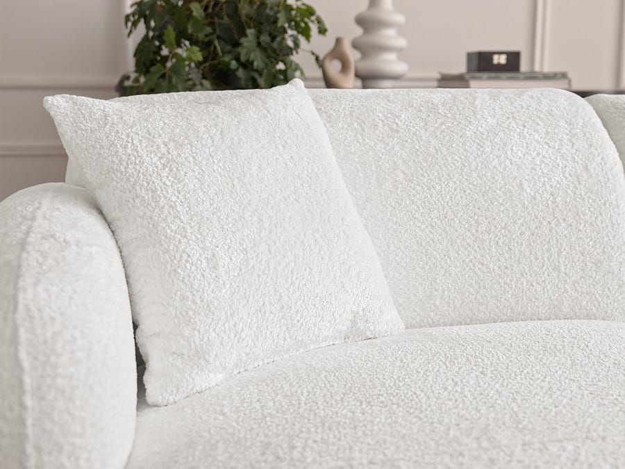 Gros plan sur les coussins et l'accoudoir du canapé Anda blanc, texture du tissu