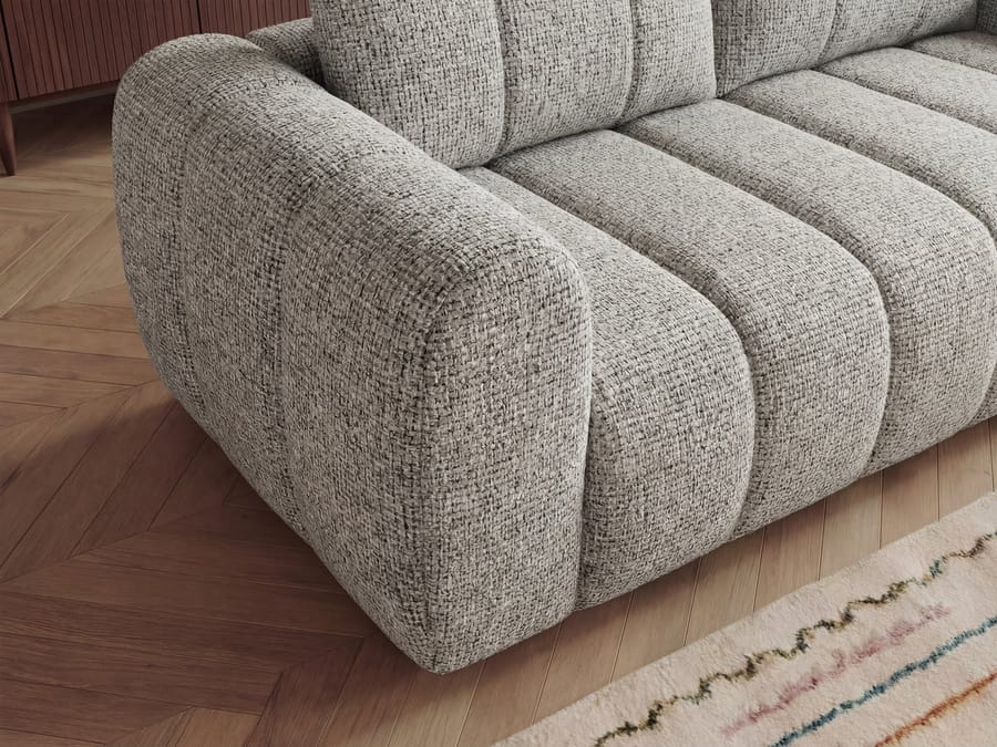Gros plan sur l'accoudoir du canapé Nesty en tissu gris avec coutures visibles