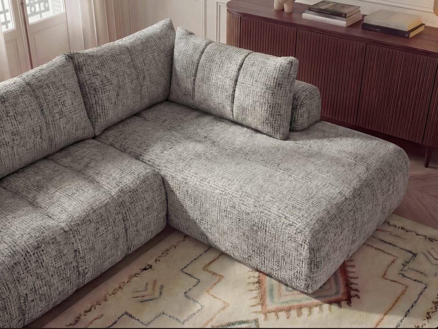Vue rapprochée de l'angle du canapé Nesty gris montrant la profondeur et les coussins