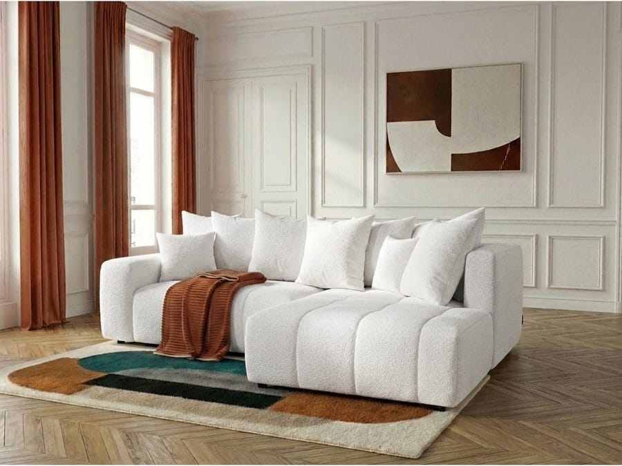 Canapé Roxelane blanc d'angle en salon blanc, table bois ronde et plaid roux