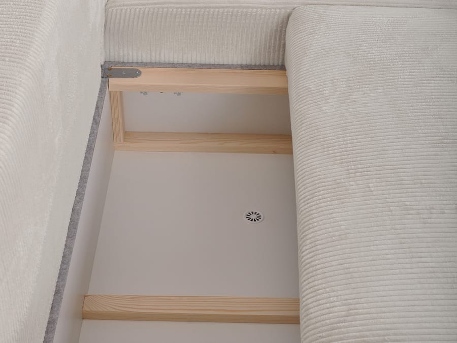 Rangement coffre ouvert sous le canapé Campi avec panneaux bois et rembourrage.